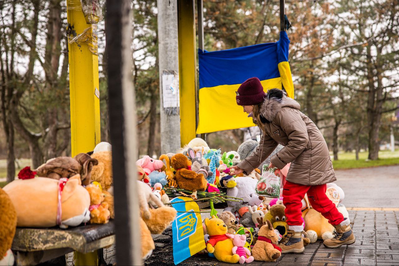 Жителі Дніпра несуть дитячі іграшки й квіти на обгорілу зупинку, яка стала місцем пам'яті